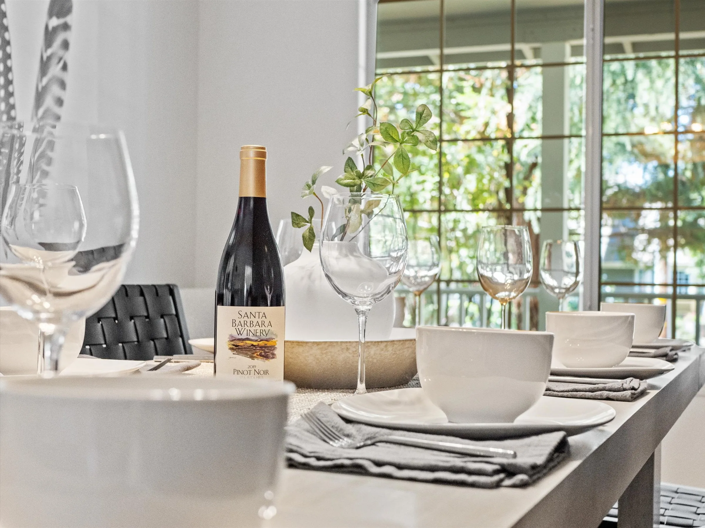 Dining table set with a bottle of Santa Barbara wine and glassware