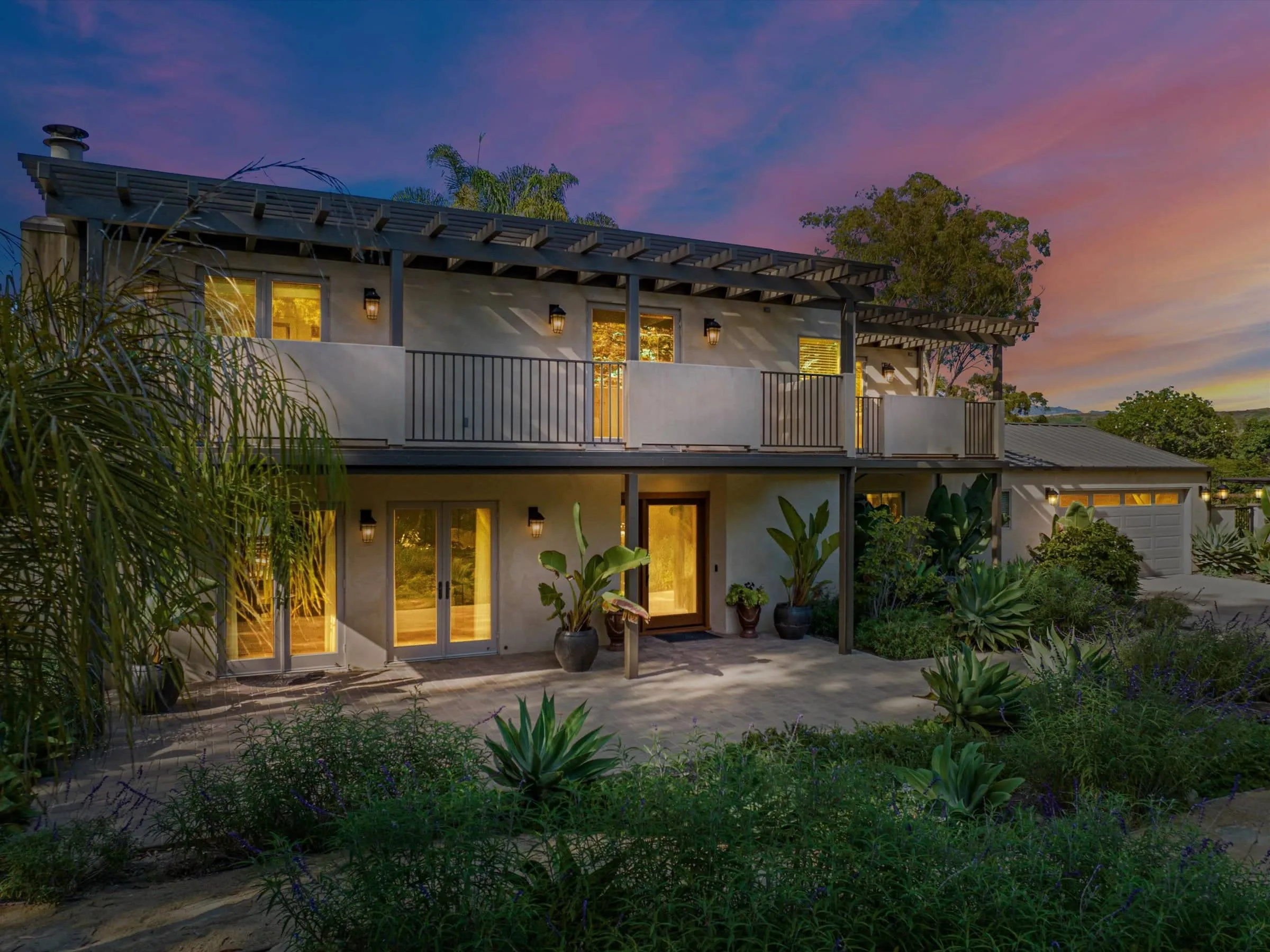 Home exterior at twilight with a warm pink sky and glowing windows