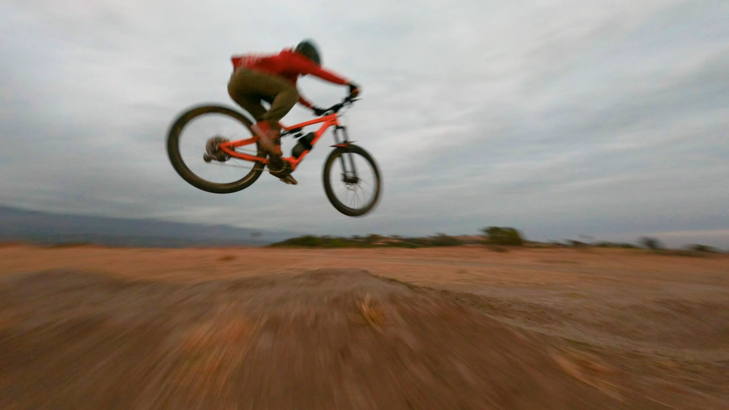 A person performing precision drone operations, riding a mountain bike in the air.