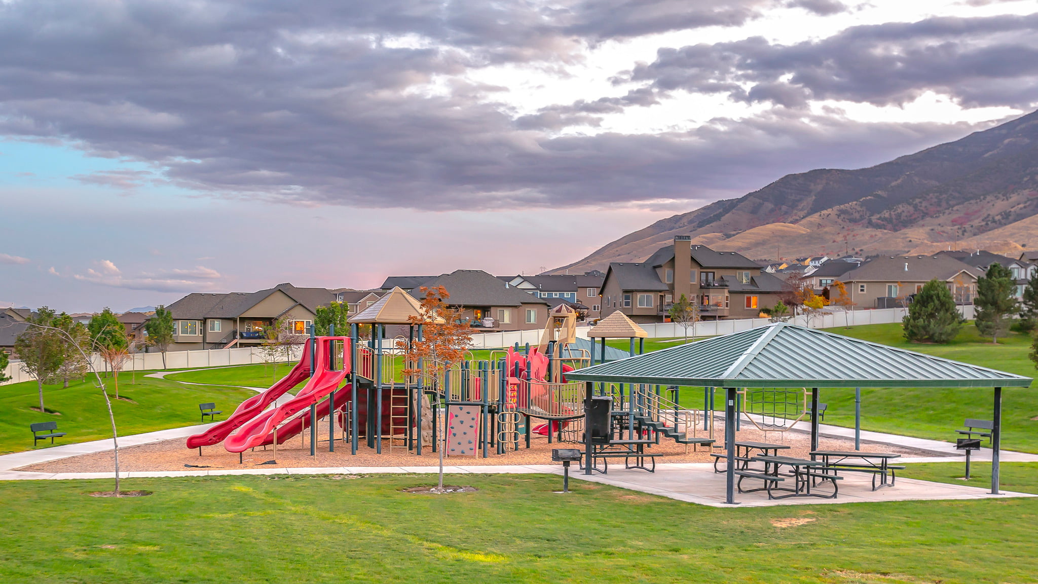 Playground set amidst a neighborhood of single-family homes with a mountain backdrop.
