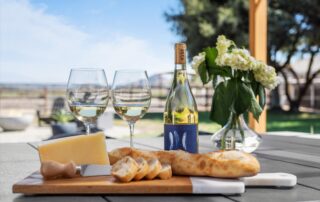 Professional photography of a serene winery drone tour set up with wine, cheese, and bread on a table overlooking vineyards